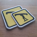 2 yellow and black embroidered patches of Canoehead portage sitting on a wooden desk