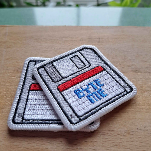 Floppy disk Byte-Me Embroidered Patch, resting on a wooden background.  Made in Canada